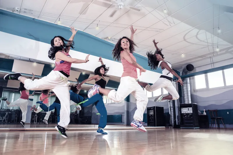 Women perform dance moves in a dance studio.