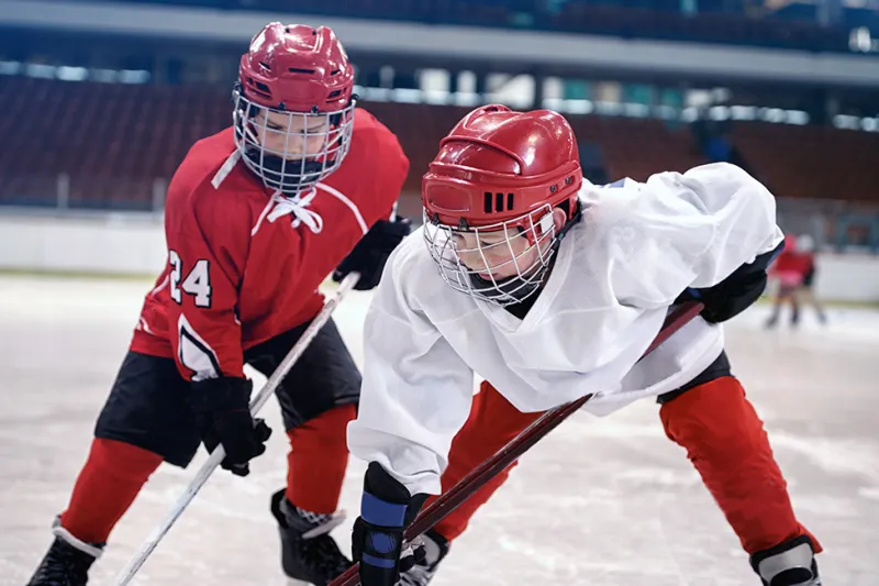 Two players battle for the puck along the rink boards