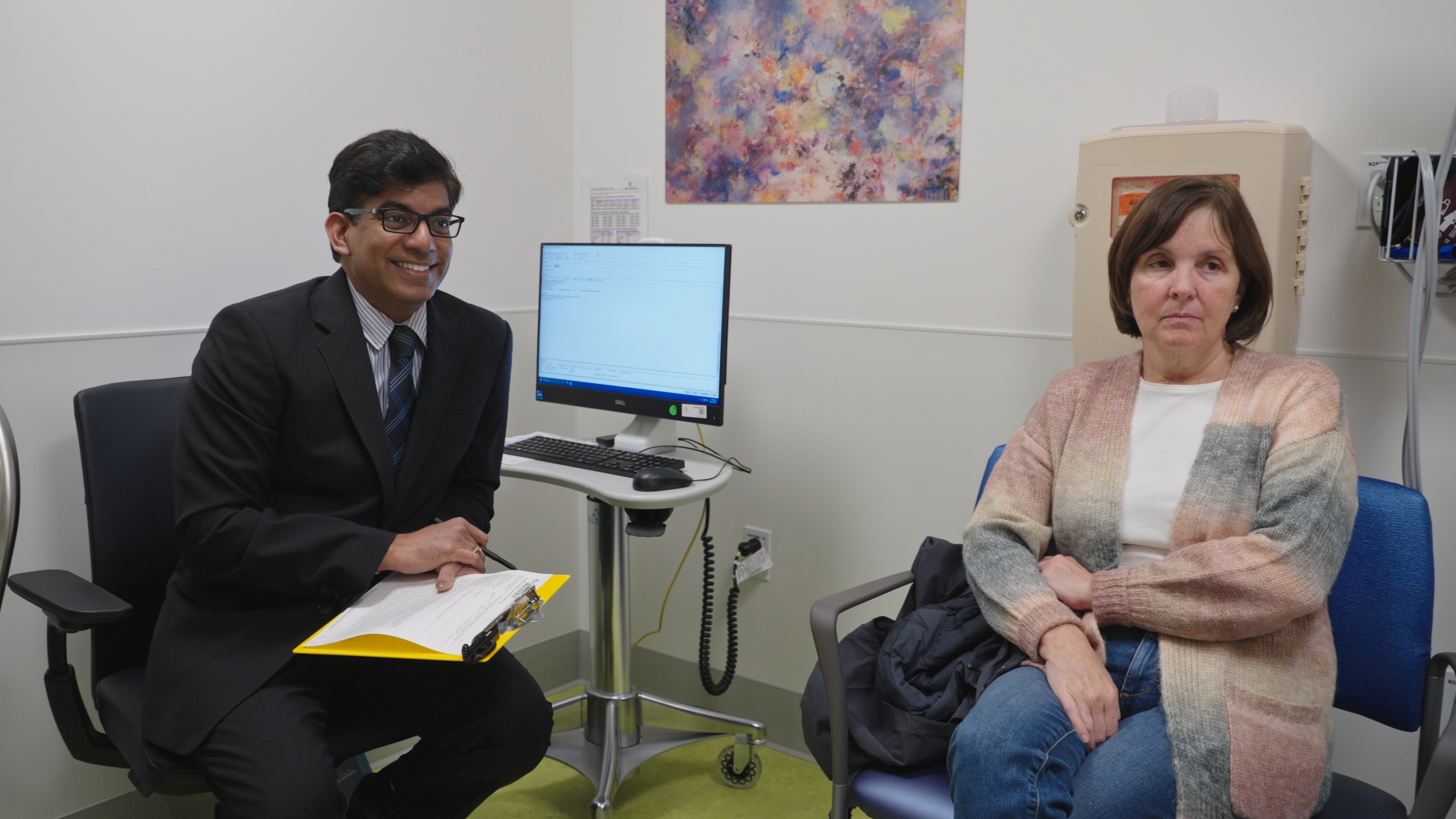 Doctor sits in office with woman