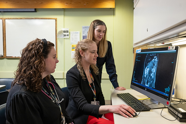 Three female music therapists looking at a MRI scan on a monitor