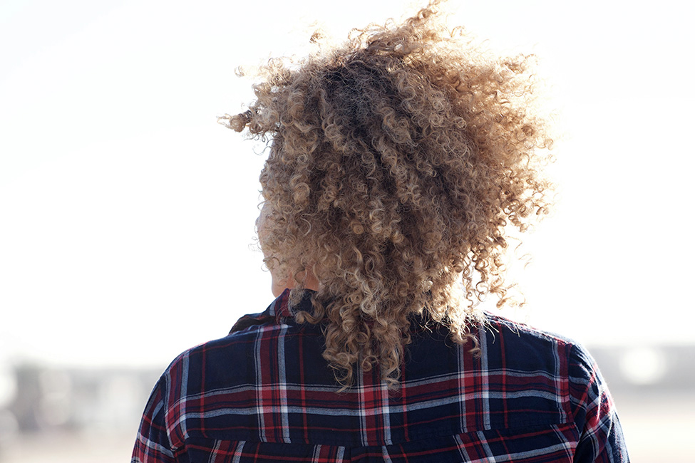 Adult with curly hair with back to camera