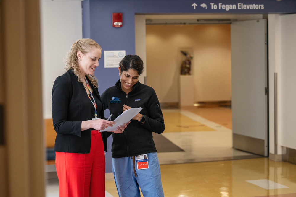 Two female clinicians stand in corridor and review document