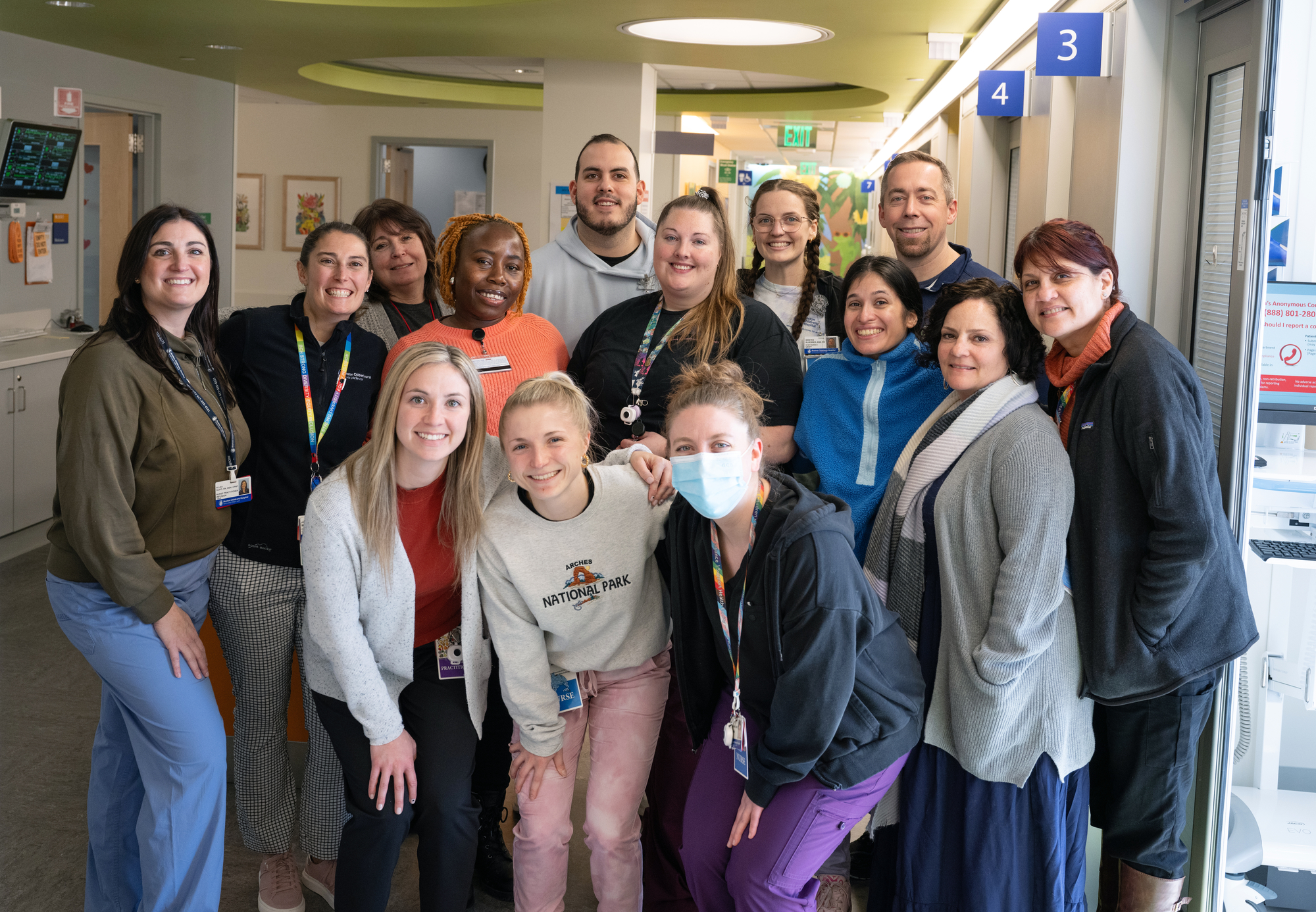 14 people (12 women, 2 men) pose for photo in hospital ward corridor