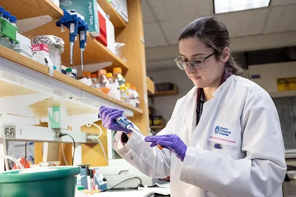 a woman wearing a coat and gloves using a pipette