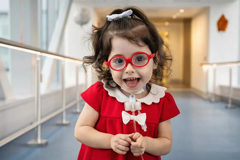 Girl smiles for camera while posing for photo on skybridge
