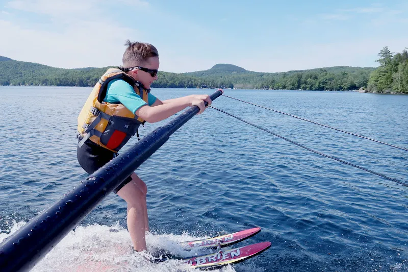 Young boy holds onto rope from boat while water skiing