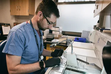 Man wearing scrubs in lab with test tubes