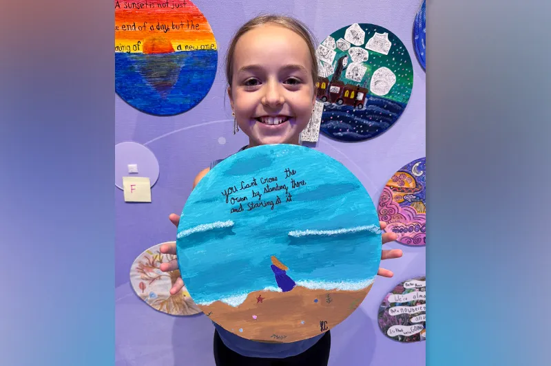 Small girl holds circular painting for the camera