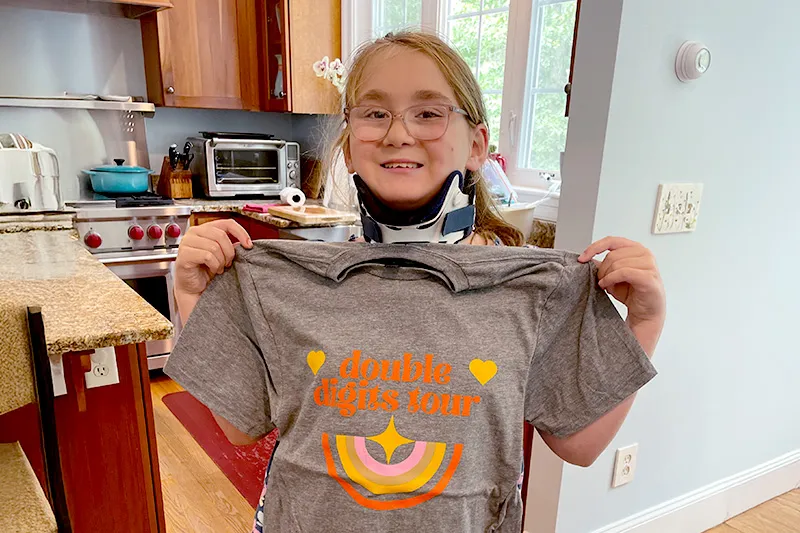 Girl wearing glasses holds up T-shirt