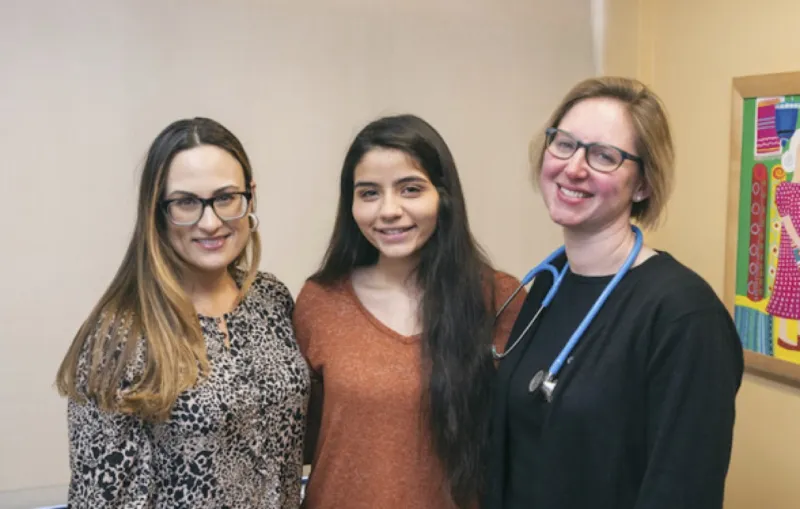 Patient stands between two of her clinicians