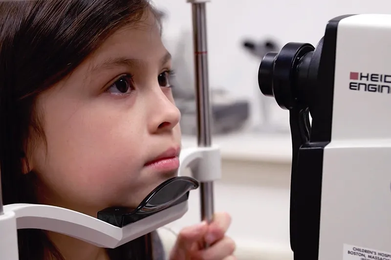 a girl putting her face in an eye reading machine.