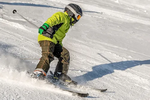 Child wearing helmet and goggles skis down hill