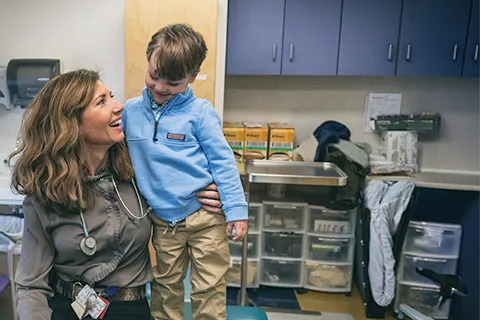 Woman holds young boy in her arms in exam room