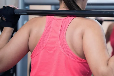 Weight lifter holds bar behind their neck