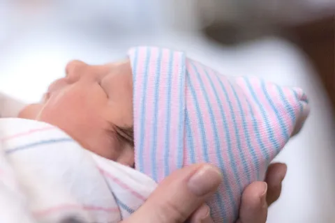 Person holds small newborn in their hands